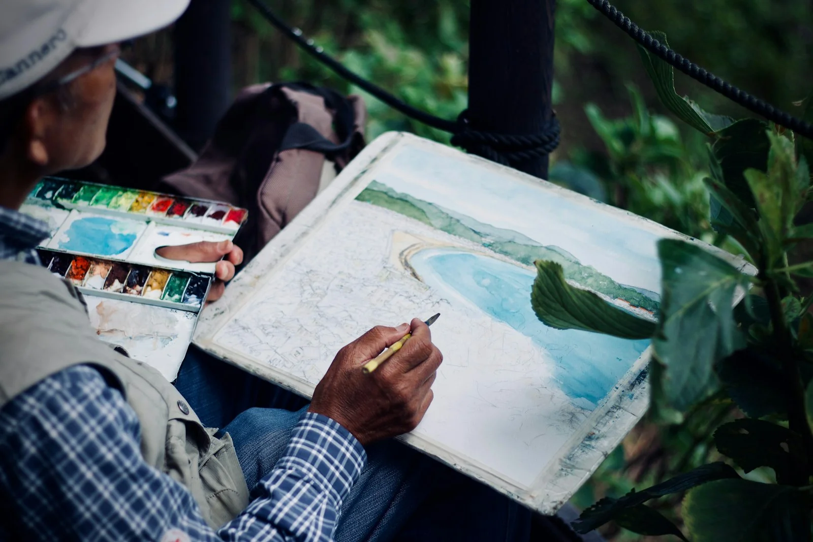An artist painting a landscape in watercolour outdoors
