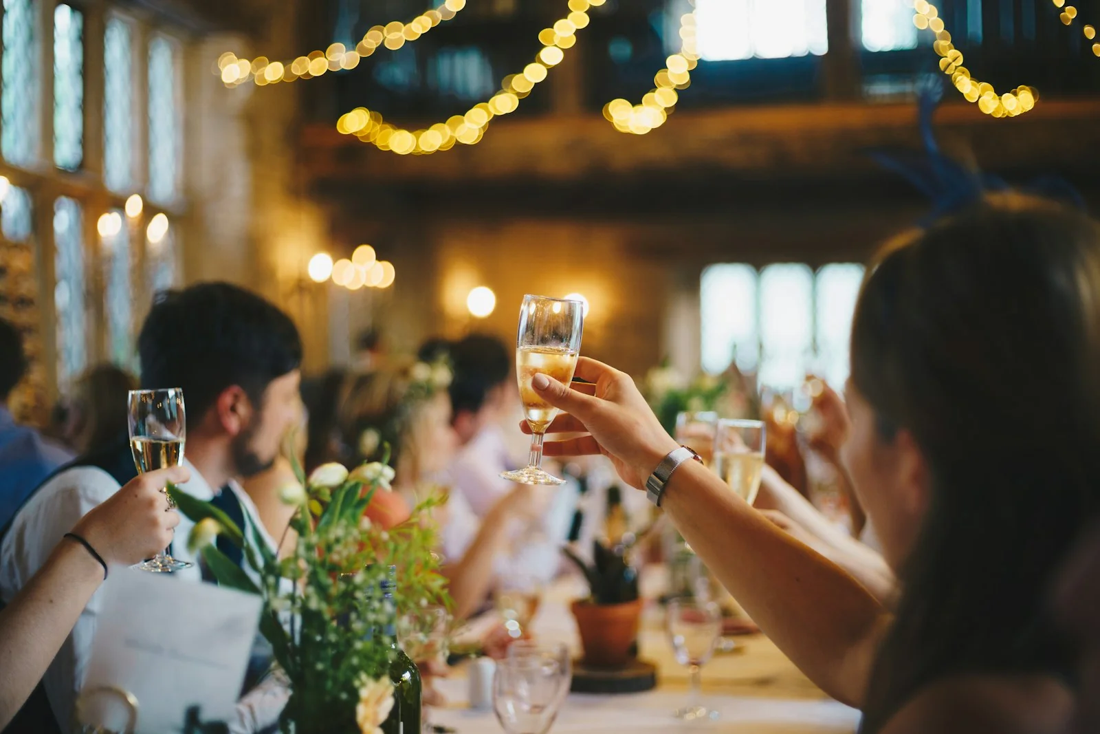 Wedding guests raising a toast under string lights